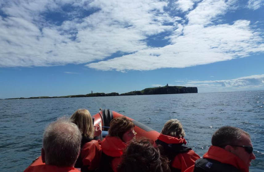 People on a rib boat with the May Isle in the background