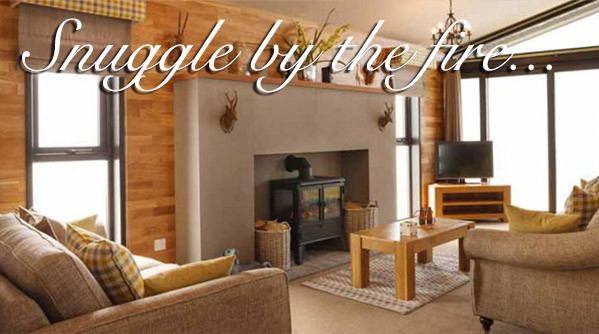 Sitting area around a stove fireplace in a lodge at Silverdyke Park with text saying snuggle by the fire
